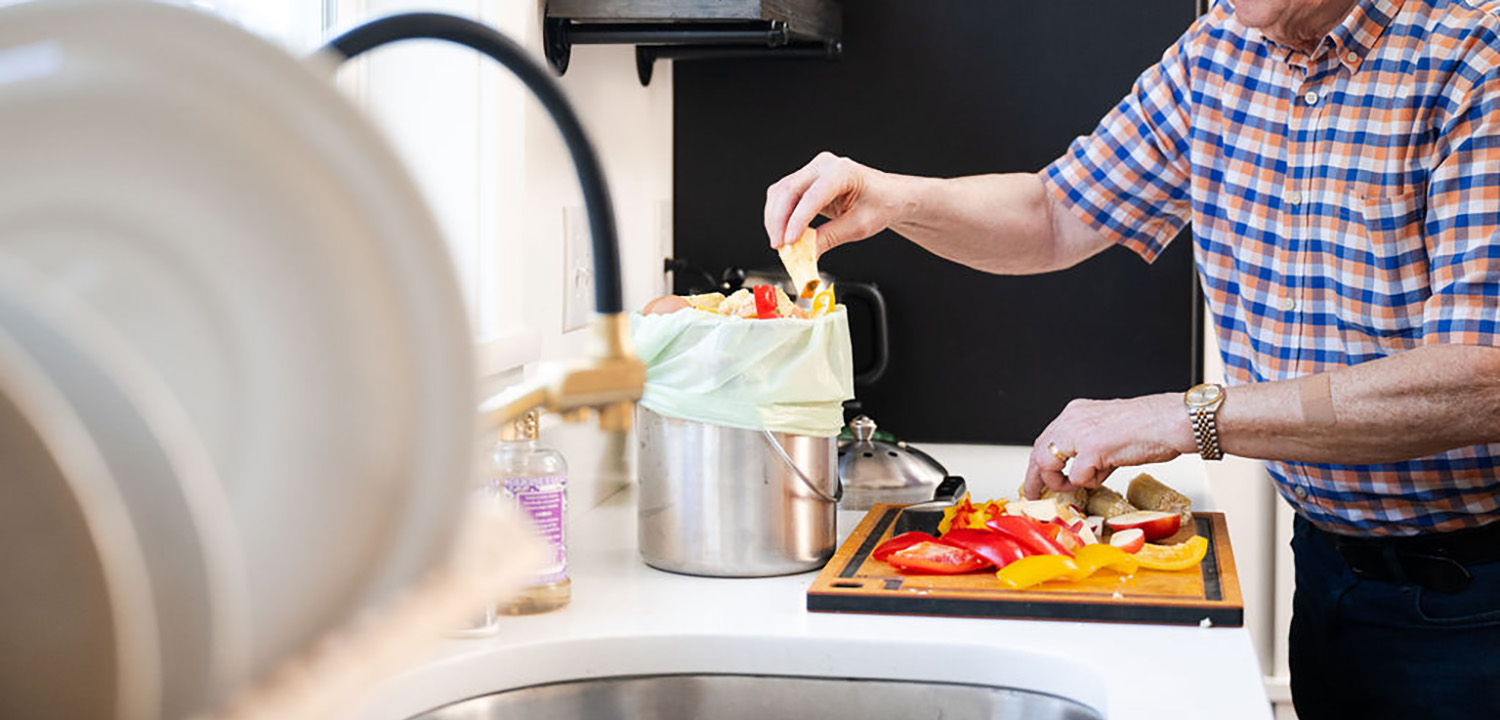 Person in kitchen filling food scraps bag